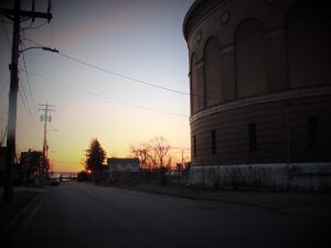 brick faced steel water tower and community garden and industrial port at sunrise